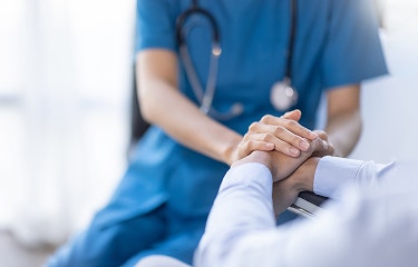 Healthcare professional holding a patient's hands