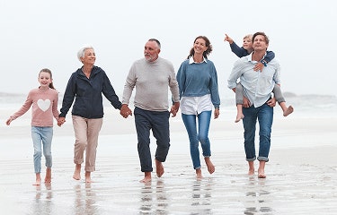 Actor portrayal of a family walking barefoot together along a beach shoreline