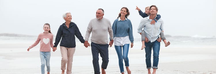 Actor portrayal of a family walking barefoot together along a beach shoreline